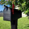 black aluminum mailbox on lawn with flag raised