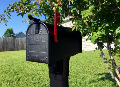 black aluminum mailbox on lawn with flag raised