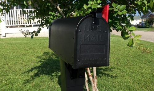 black aluminum mailbox on lawn with flag raised