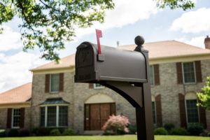bronze mailbox with eagle embossing on door in front of large home